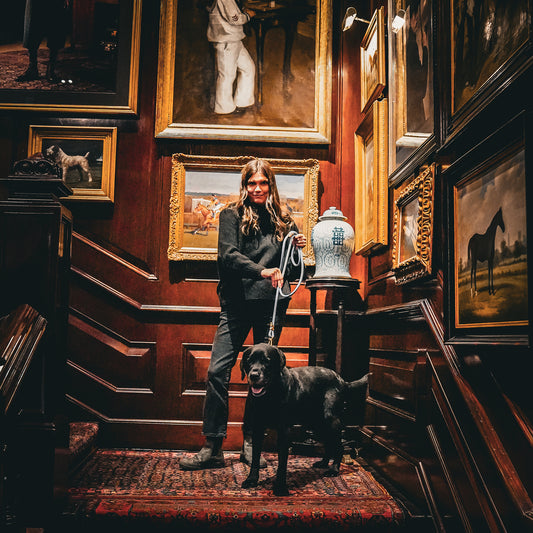 Elegant Woman with a dog in a room with wooden walls and framed paintings