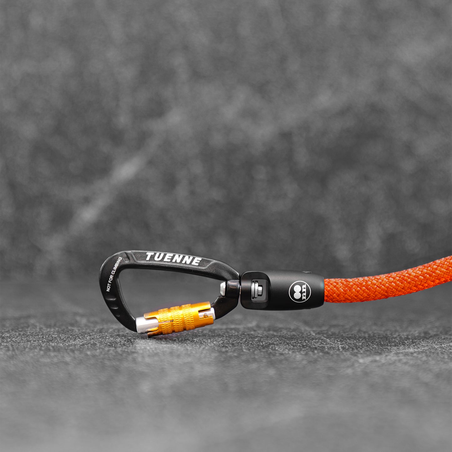 Carabiner with blood orange rope dog leash on a gray background.