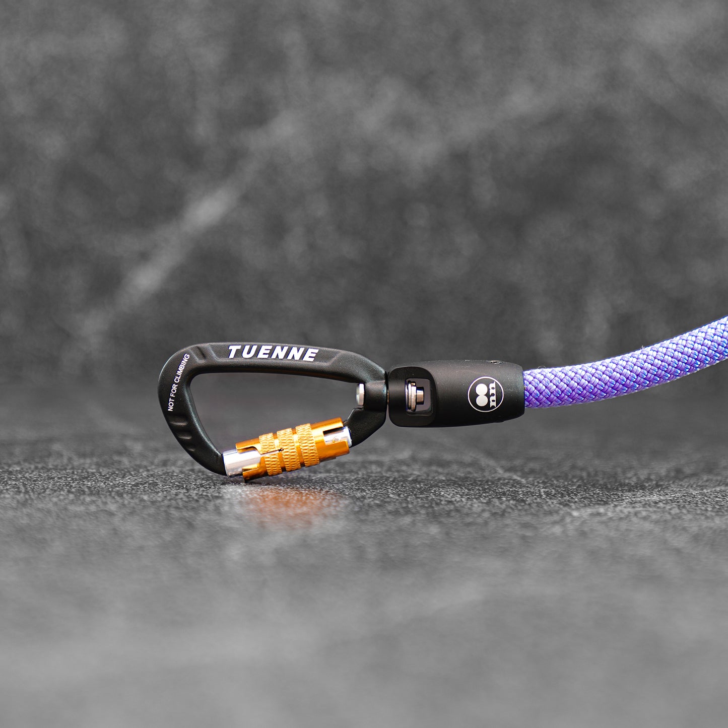 detailed photo of the carabiner on a lavender color climbing rope dog leash on a slate background