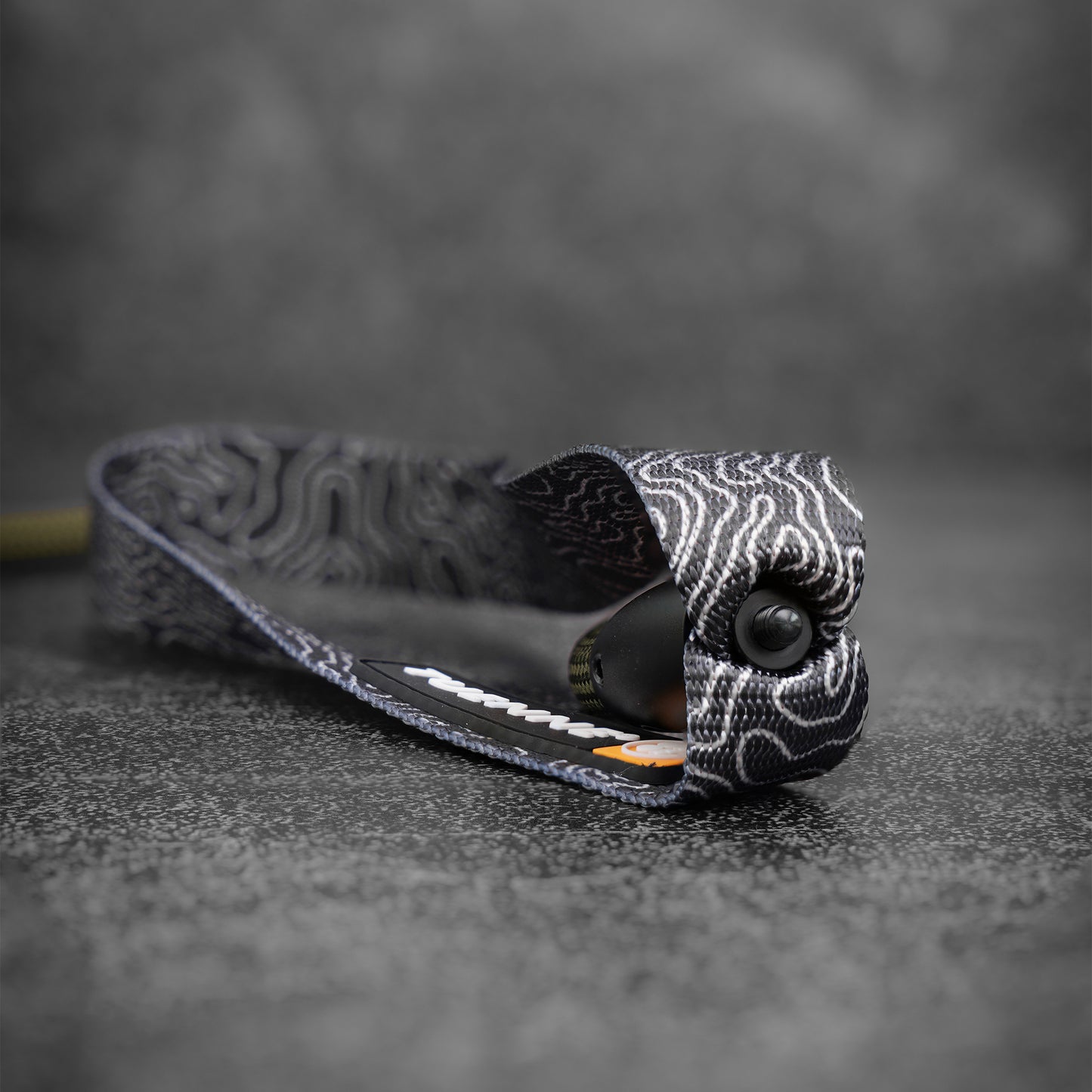 Black and white topographic patterned webbing dog leash handle on a textured gray surface with a blurred background