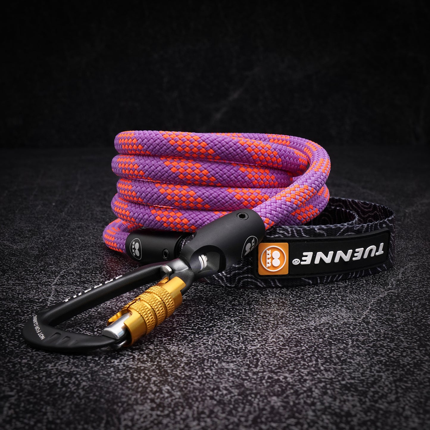 Close-up of coiled purple and orange climbing-rope dog leash with black auto-locking carabiner