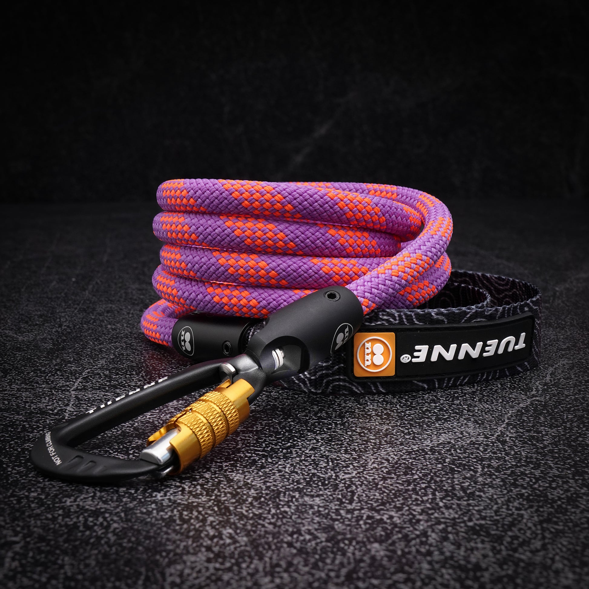 Close-up of coiled purple and orange climbing-rope dog leash with black auto-locking carabiner