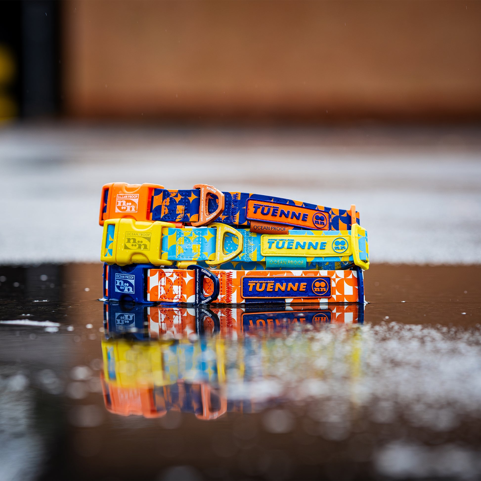 Stack of colorful collars with 'TUENNE' branding on a reflective surface.