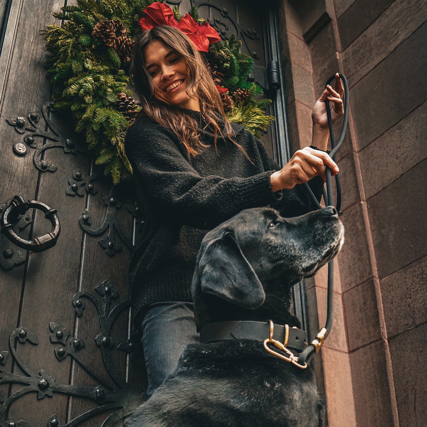 Woman with a dog standing in front of a decorative church door with a wreath.