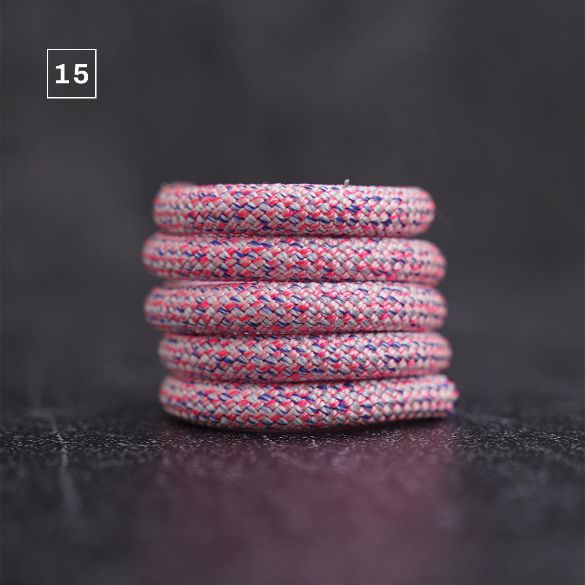 A stack of five braided rope loops in a marled pink, red, and blue colorway, set against a dark, textured background with a '15' label in the top-left corner.