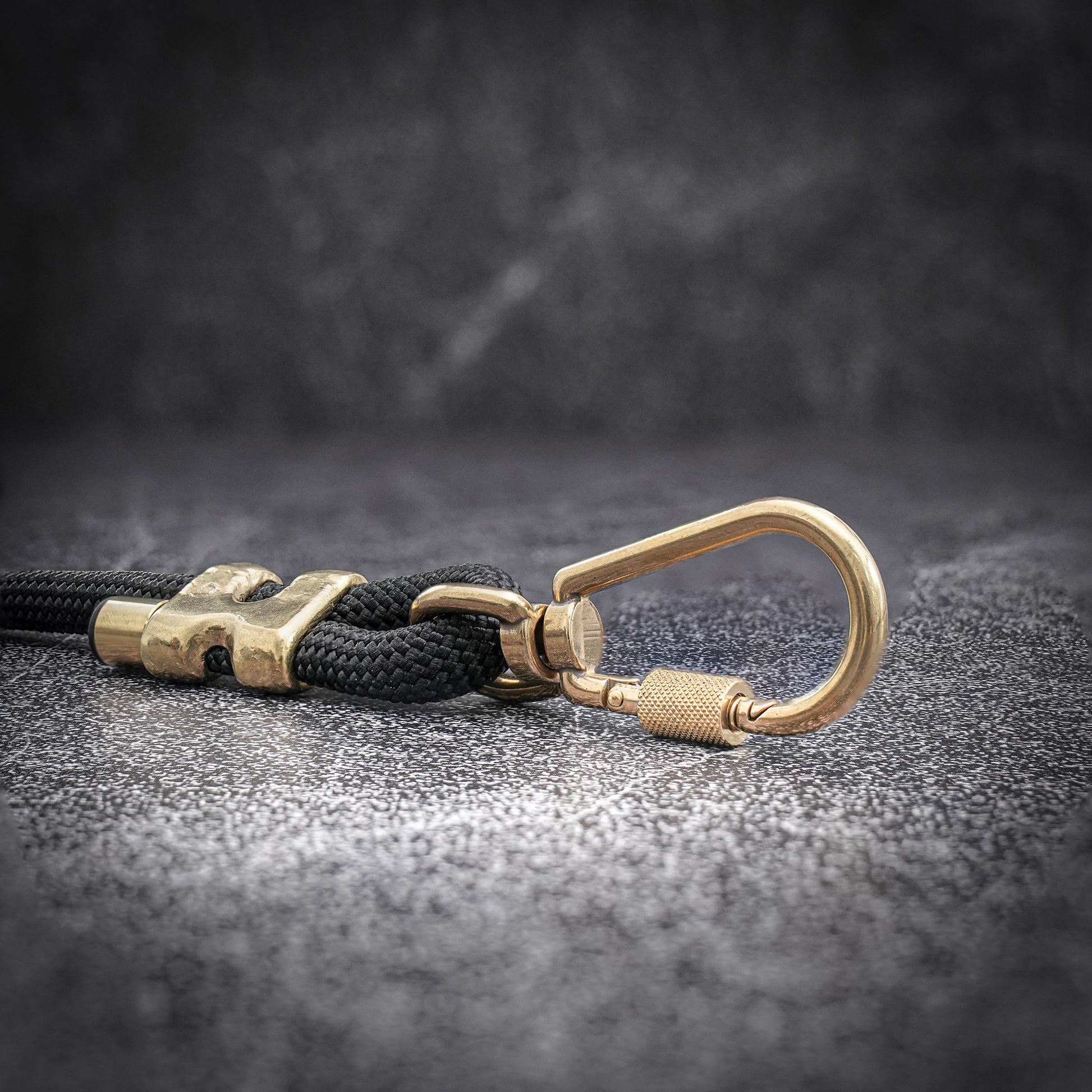 Brass dog leash with black rope on a dark textured surface