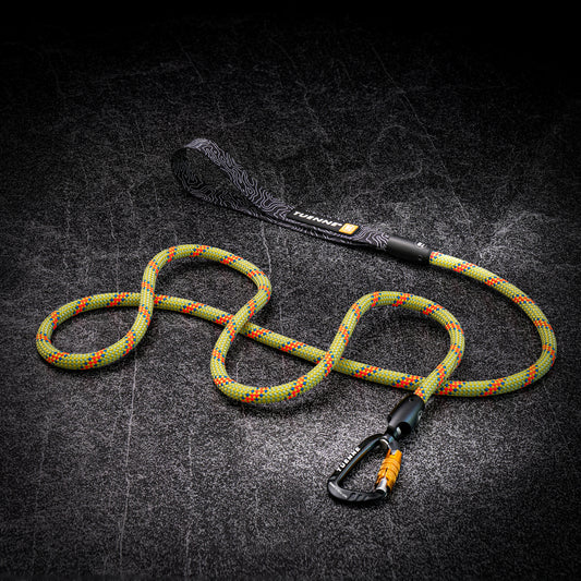 A green and orange climbing rope with a black loop handle and black carabiner, displayed on a dark textured background.