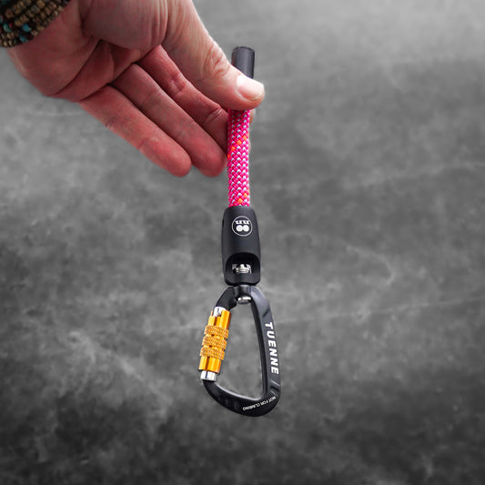 Hand holding a carabiner keychain with pink rope against a gray background