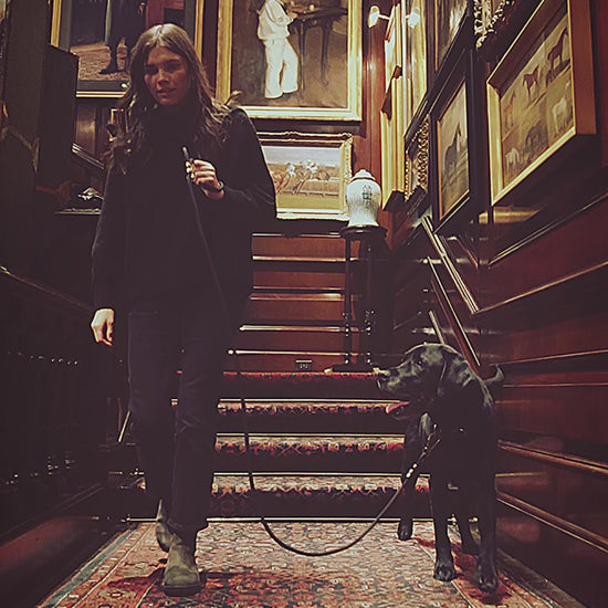 elegant woman with dog in room filled with old gold leaf picture frames.