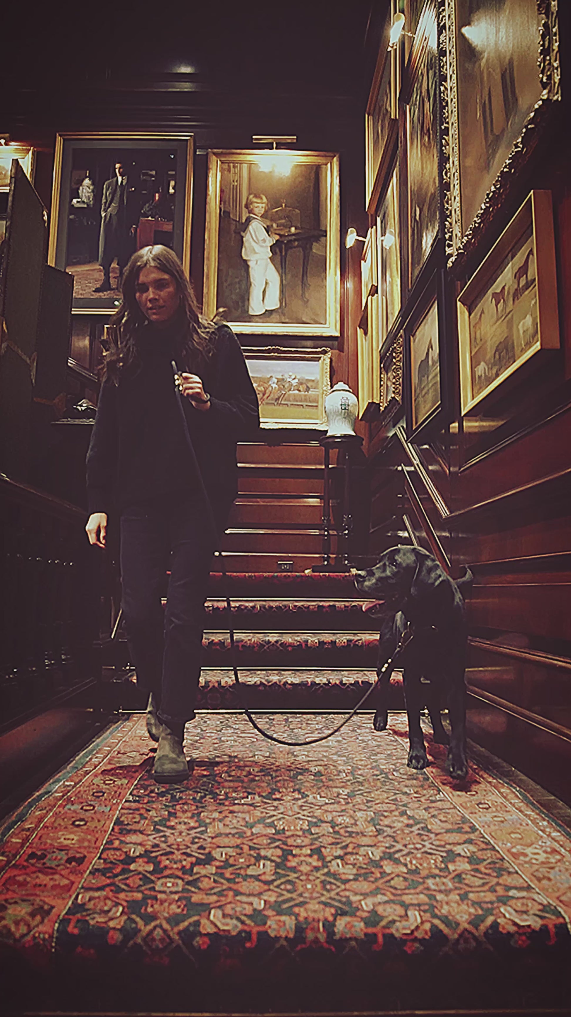 elegant woman with dog in room filled with old gold leaf picture frames.
