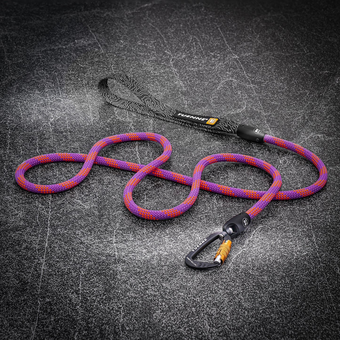 Purple and pink climbing-rope dog leash with auto-locking carabiner laid out on a dark textured surface