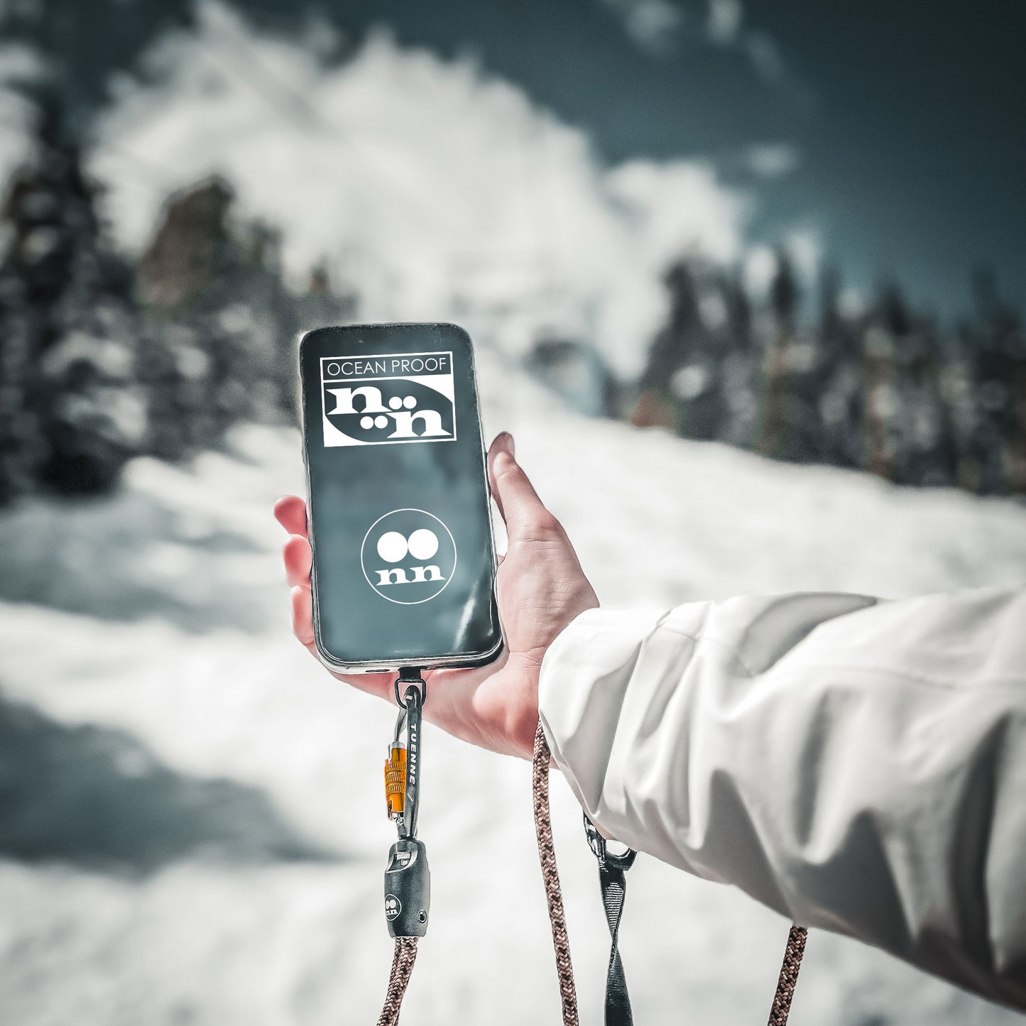 Person holding Tuenne lanyard with phone attachment on a mountain, showcasing outdoor versatility