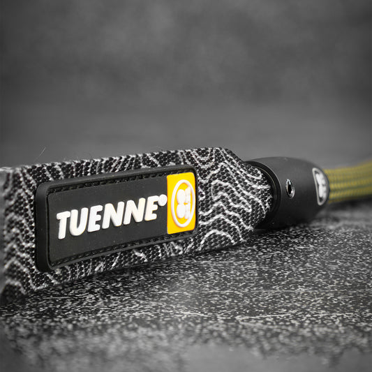 Black and yellow TUENNE branded dog leash handle on a textured surface