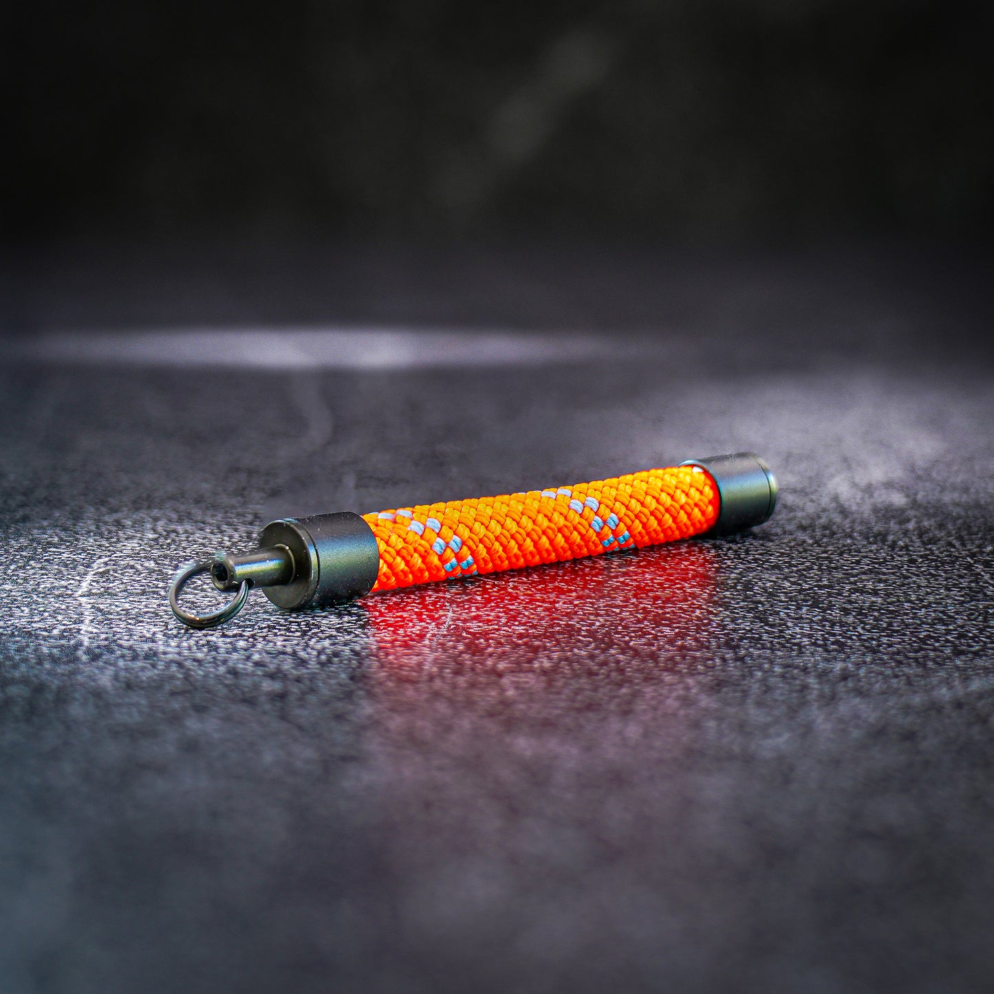 Orange rope keychain on a dark textured surface